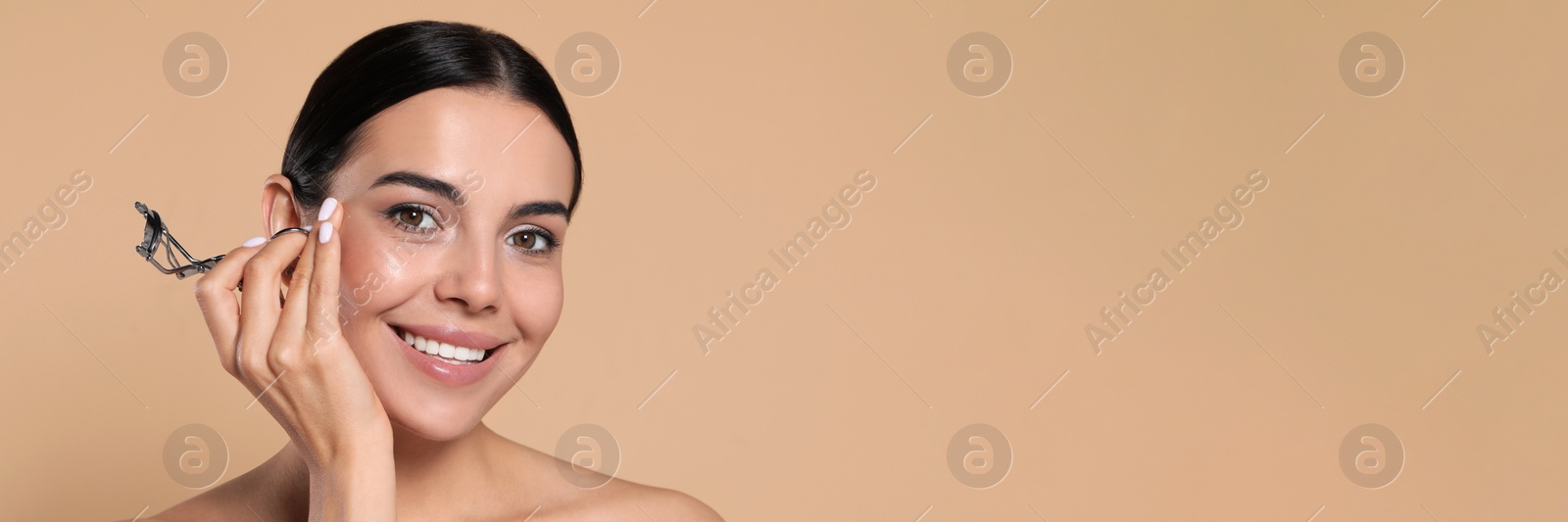 Image of Beautiful young woman with eyelash curler on beige background, space for text. Banner design