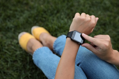 Photo of Woman using modern smart watch outdoors, closeup