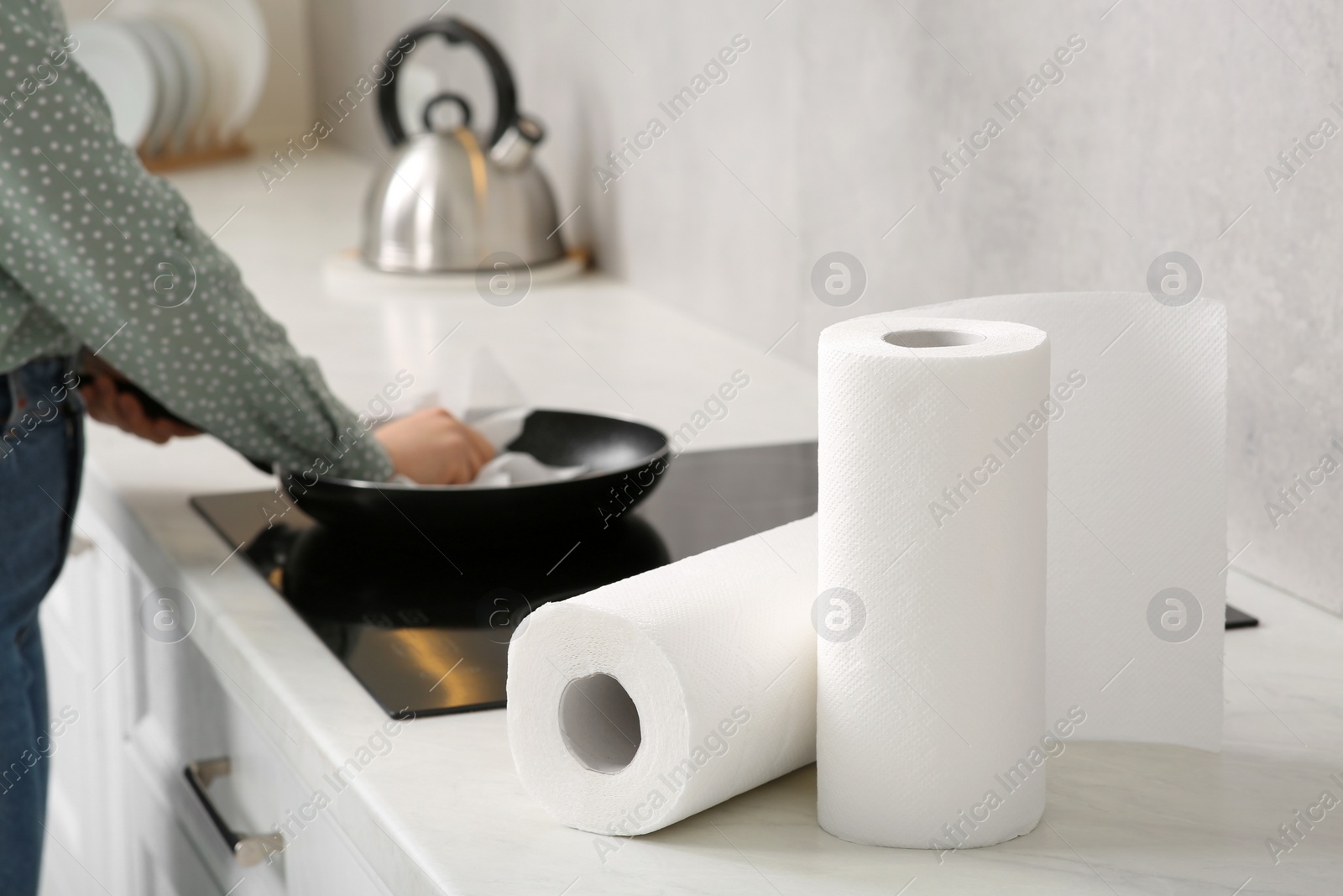 Photo of Woman wiping frying pan with paper towel in kitchen, selective focus. Space for text