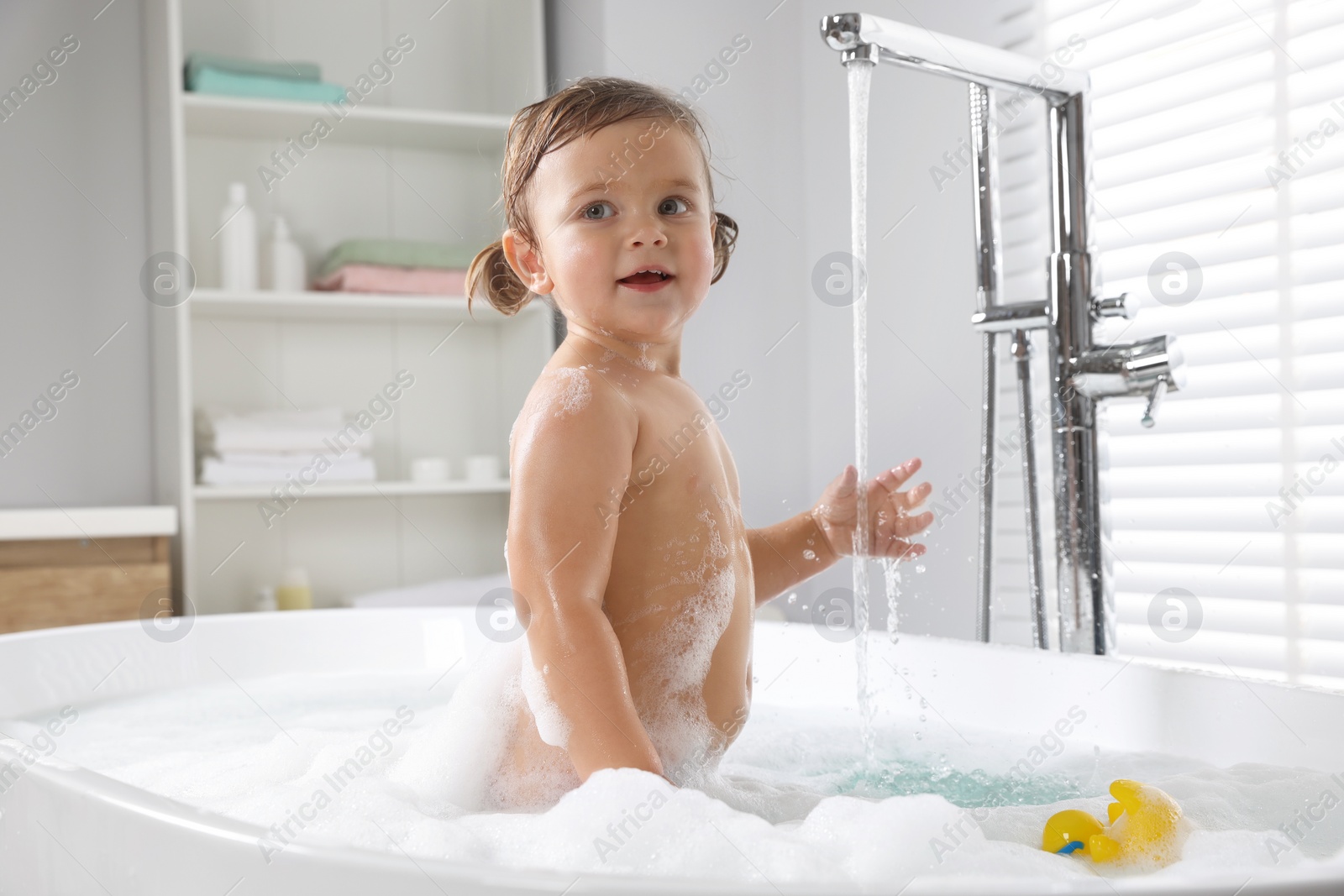 Photo of Cute little girl in foamy bath at home