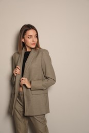 Portrait of beautiful young woman in fashionable suit on grey background. Business attire
