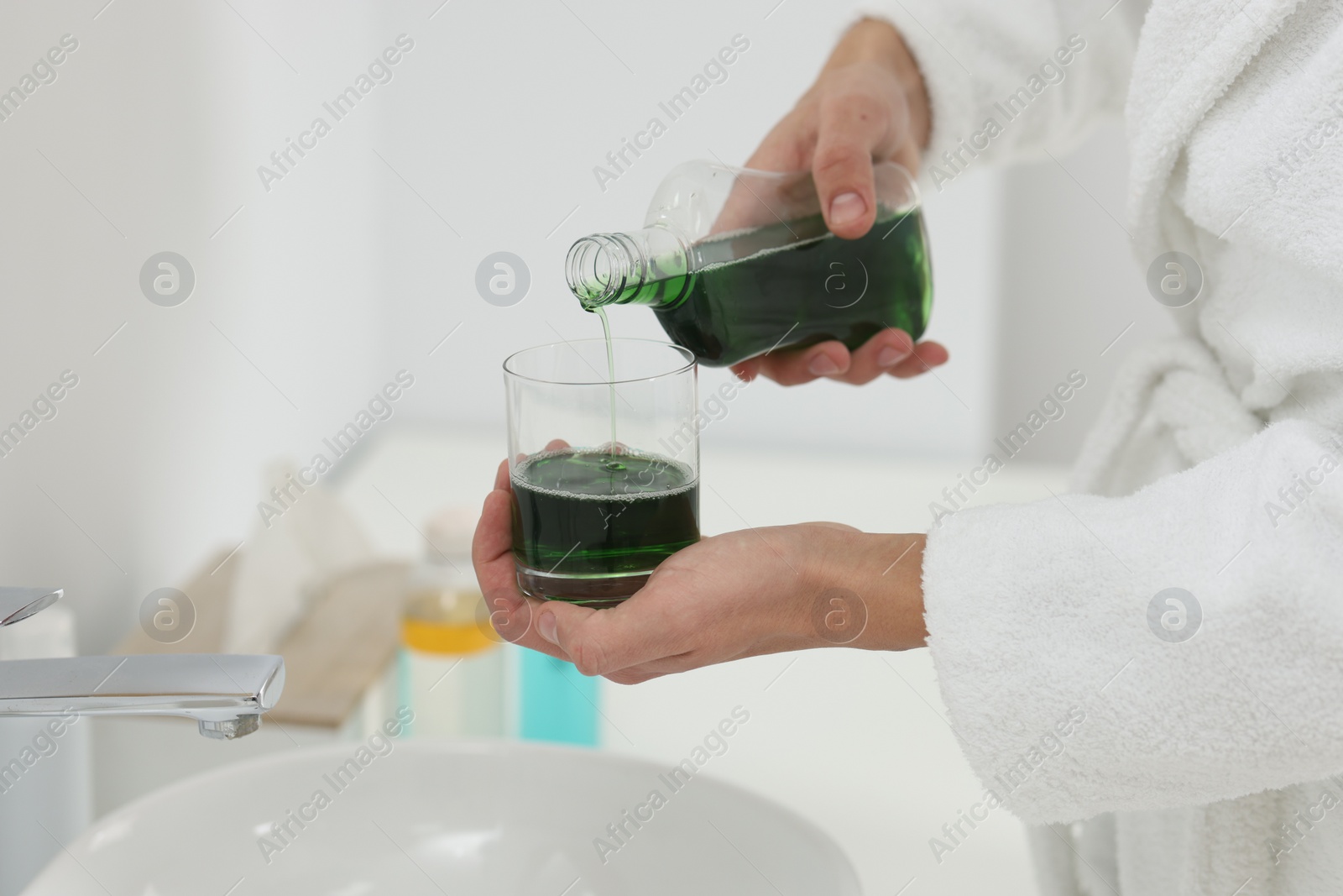 Photo of Young man using mouthwash in bathroom, closeup