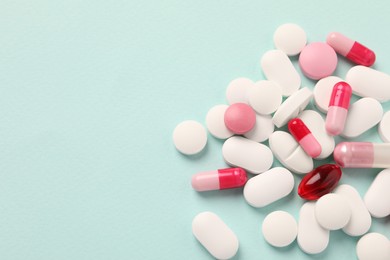 Photo of Pile of different pills on mint background, flat lay. Space for text