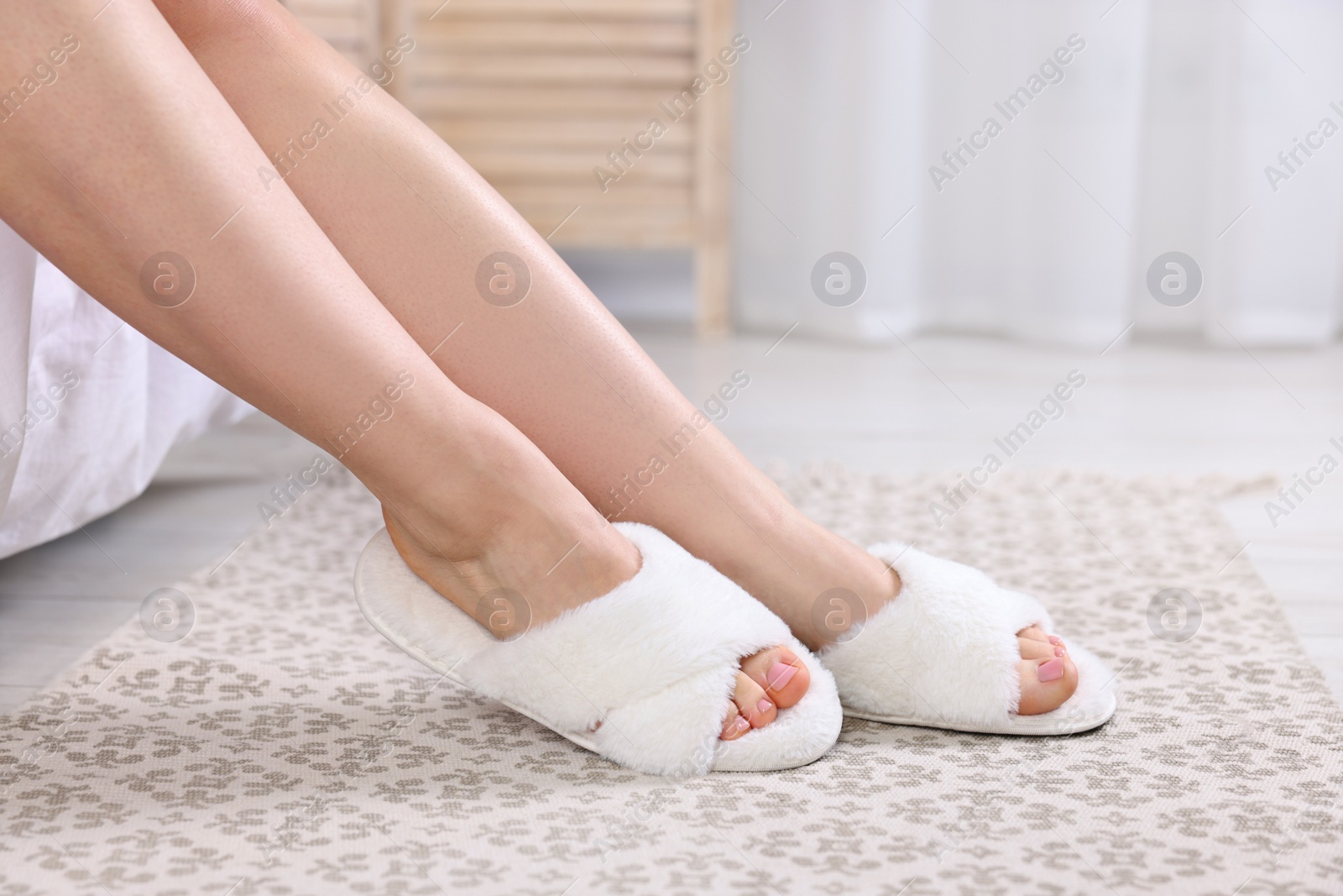 Photo of Woman in white soft slippers at home, closeup