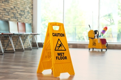 Photo of Safety sign with phrase Caution wet floor, indoors