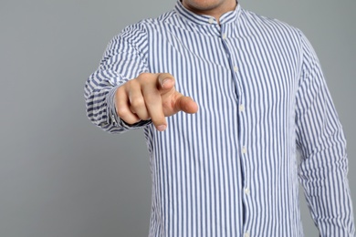 Man touching something on grey background, closeup. Finger gesture