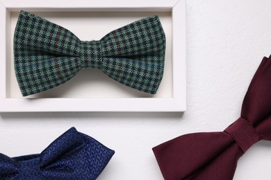 Stylish color bow ties on white textured background, flat lay