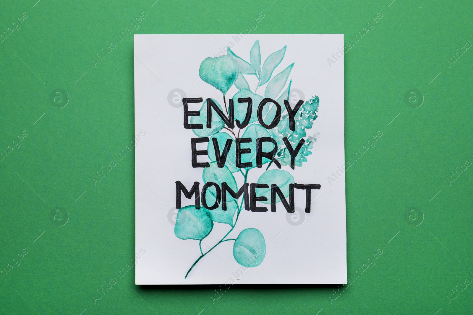 Photo of Card with beautiful phrase Enjoy Every Moment on green background, top view