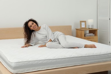 Photo of Happy young African American woman on bed with comfortable mattress at home