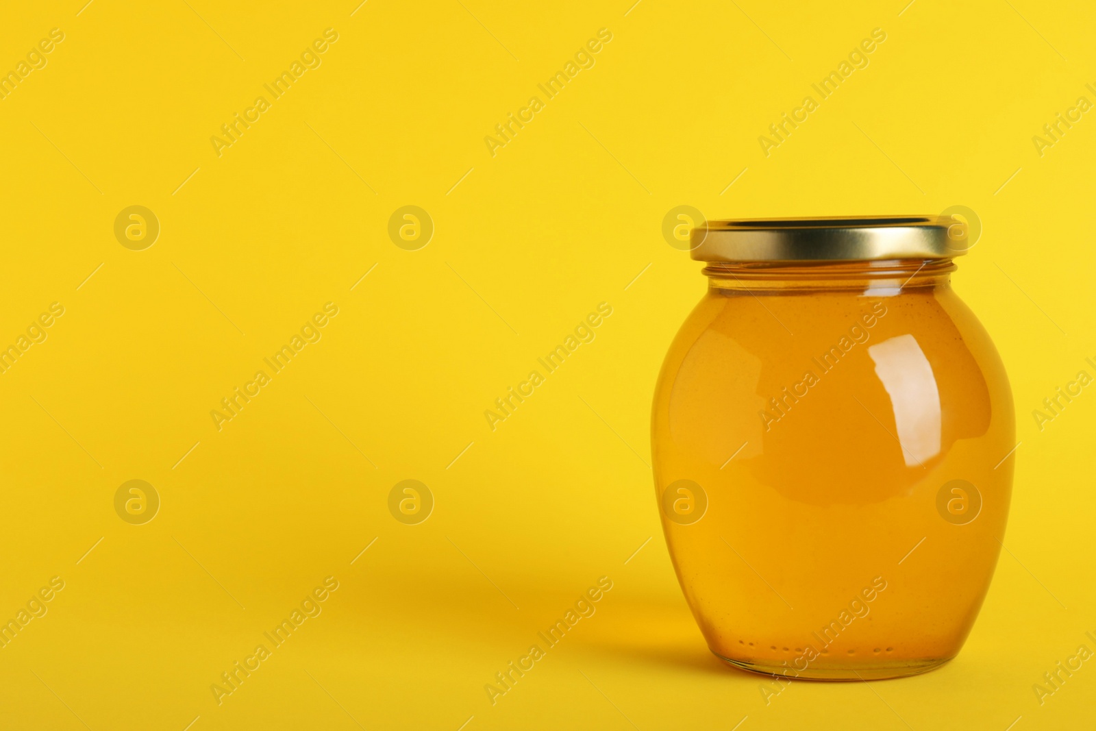 Photo of Jar of organic honey on yellow background. Space for text