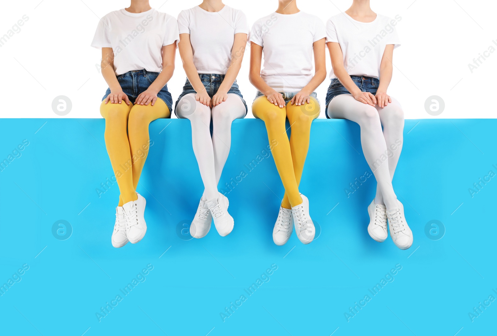 Photo of Group of women wearing colorful tights and stylish shoes sitting on color background, closeup