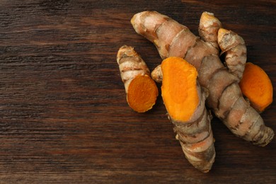 Photo of Fresh turmeric roots on wooden table, flat lay. Space for text