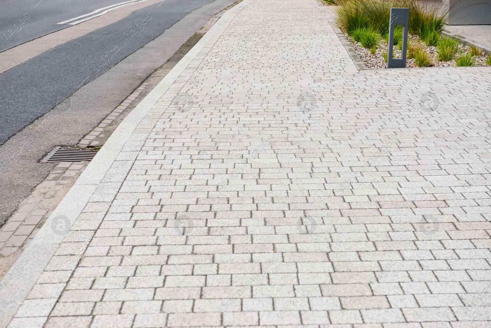 Photo of Sidewalk path near road on city street. Footpath covering