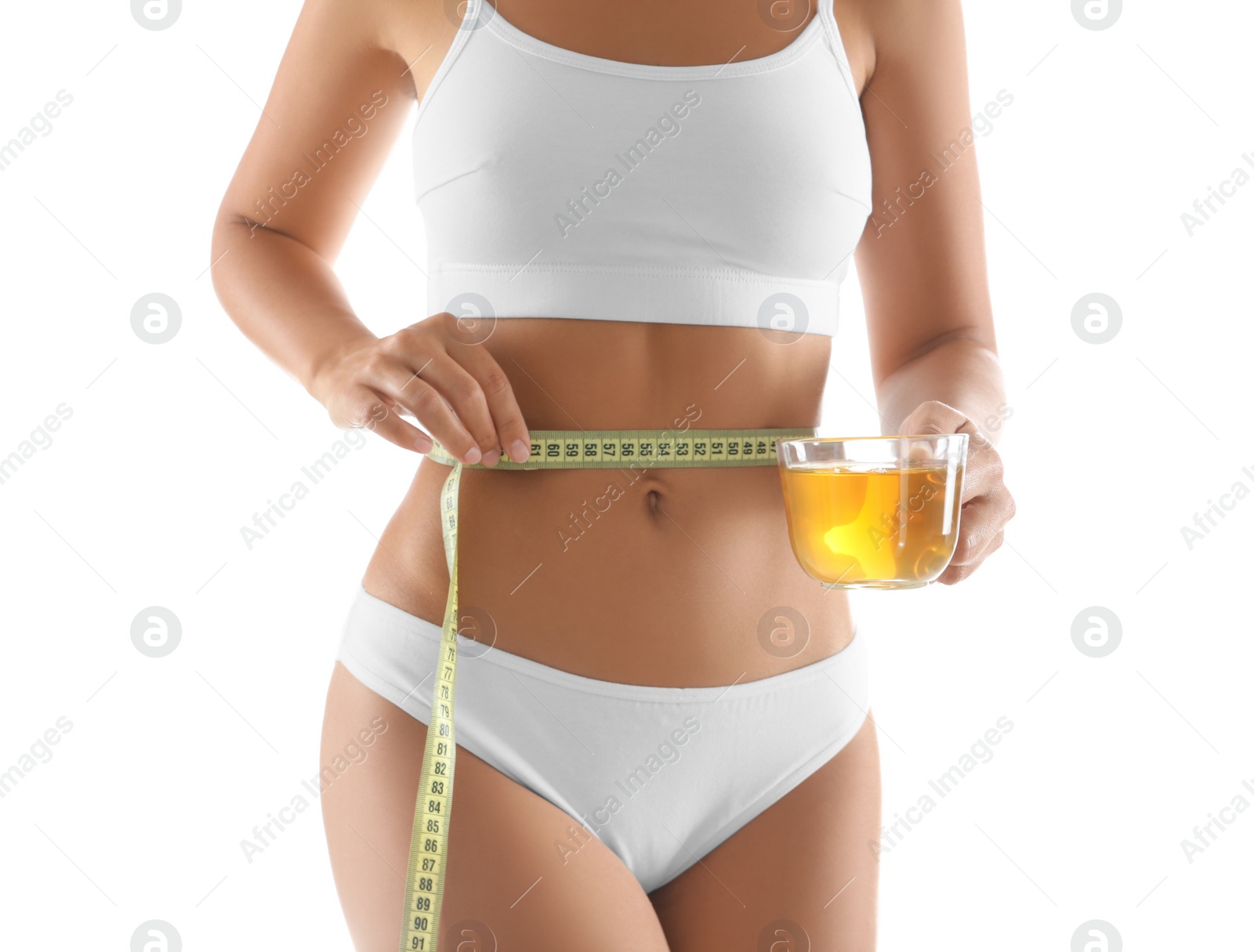 Photo of Young woman with measuring tape holding cup of diet tea on white background, closeup