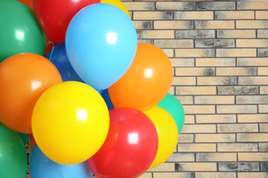 Photo of Bunch of bright balloons against brick wall