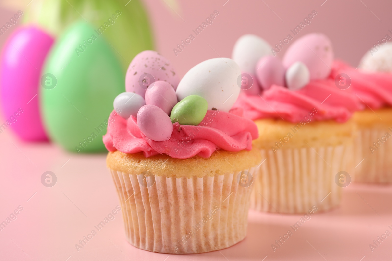 Photo of Tasty decorated Easter cupcakes on pink background, selective focus