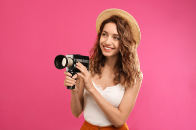 Photo of Beautiful young woman with vintage video camera on crimson background