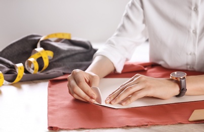 Photo of Tailor working with cloth at table in atelier