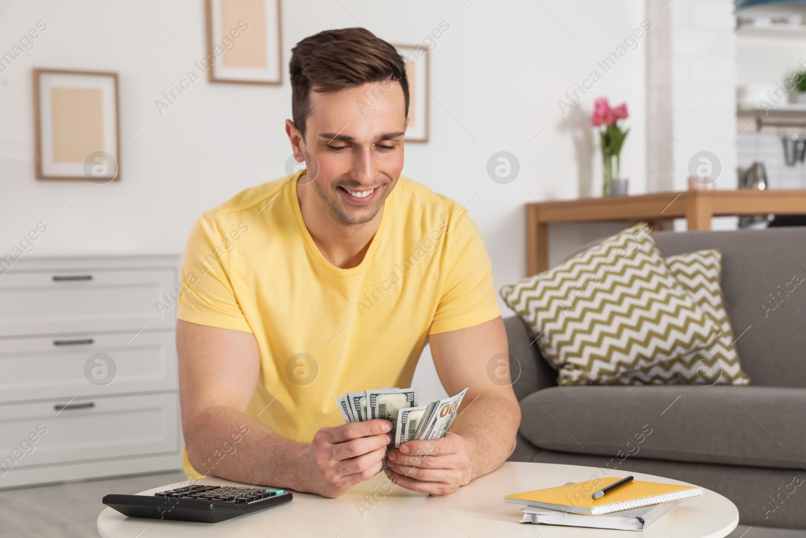 Photo of Happy man counting money at table in living room