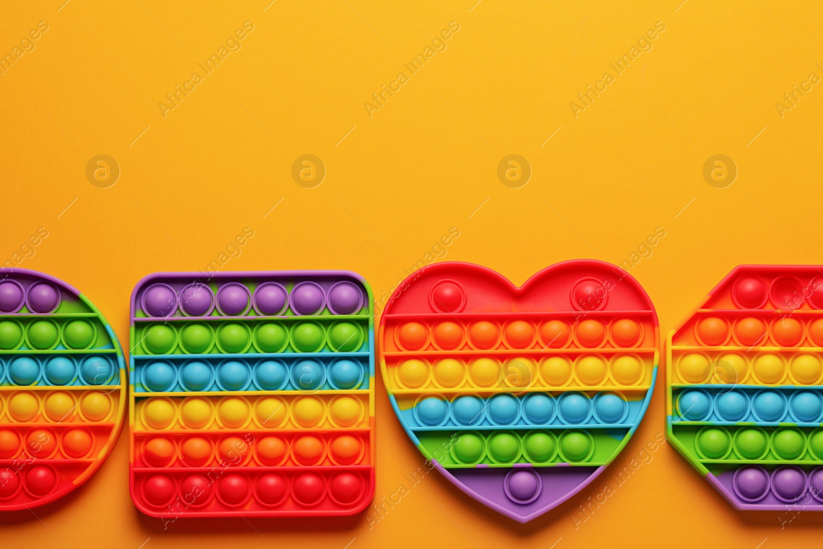 Photo of Rainbow pop it fidget toys on orange background, flat lay. Space for text