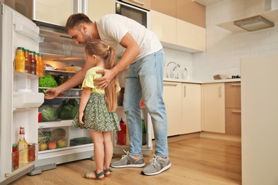 Photo of Young father and daughter choosing food in refrigerator at kitchen