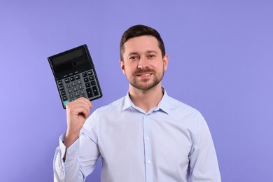 Photo of Happy accountant showing calculator on violet background