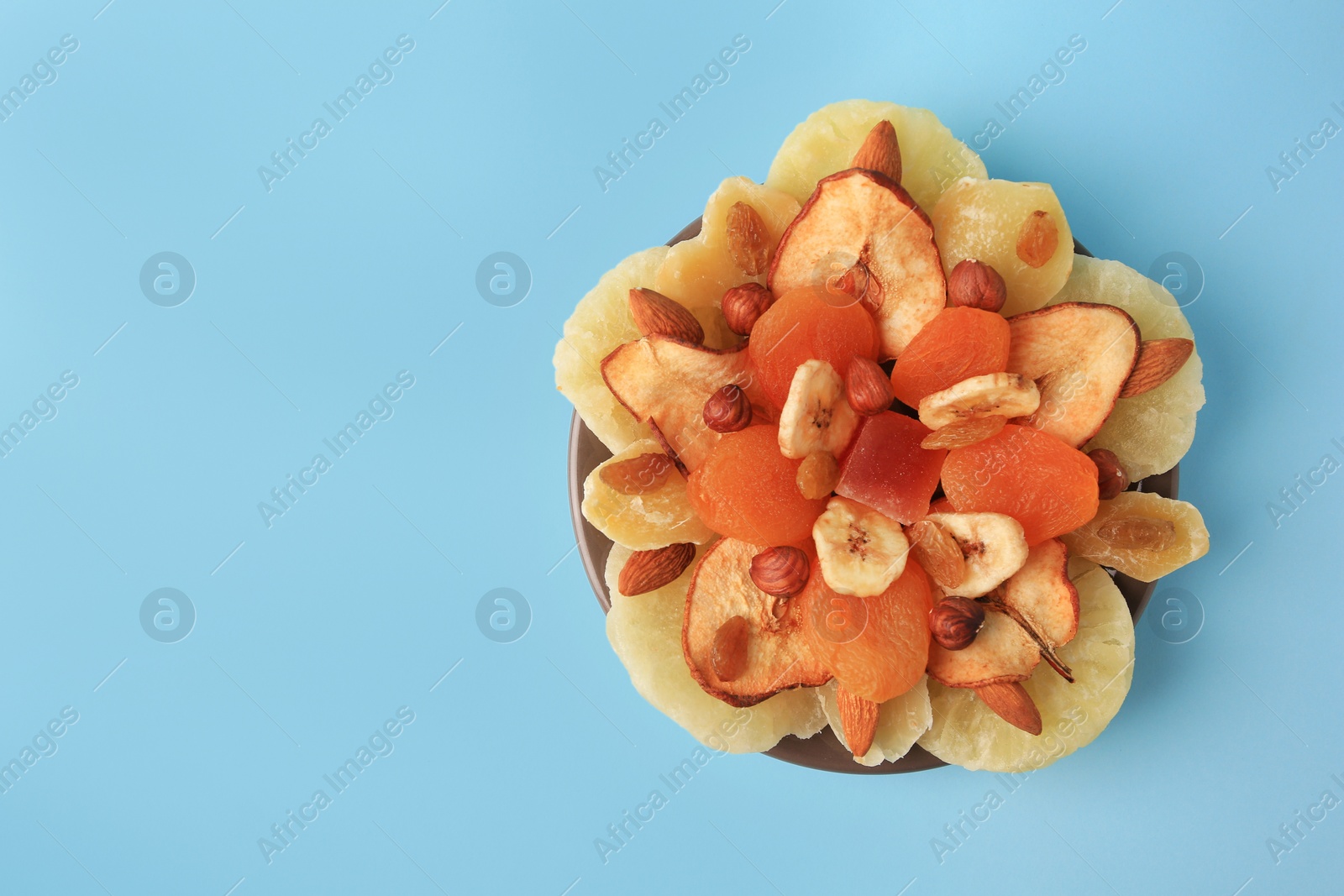 Photo of Mixed dried fruits and nuts on light blue background, top view. Space for text