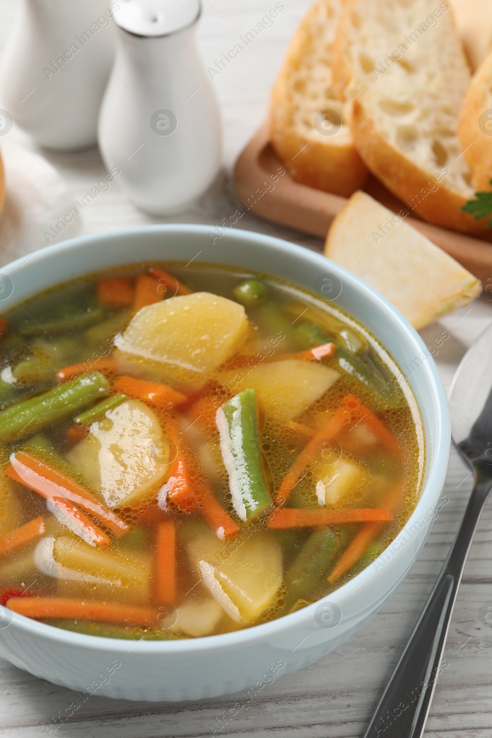 Photo of Bowl of tasty turnip soup and spoon on white wooden table