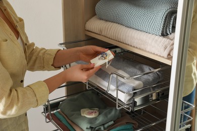 Woman putting scented sachet into wardrobe, closeup