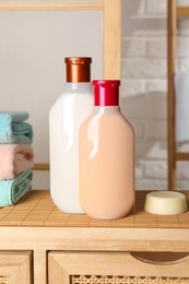 Photo of Solid shampoo bar and bottles of cosmetic product on wooden table in bathroom
