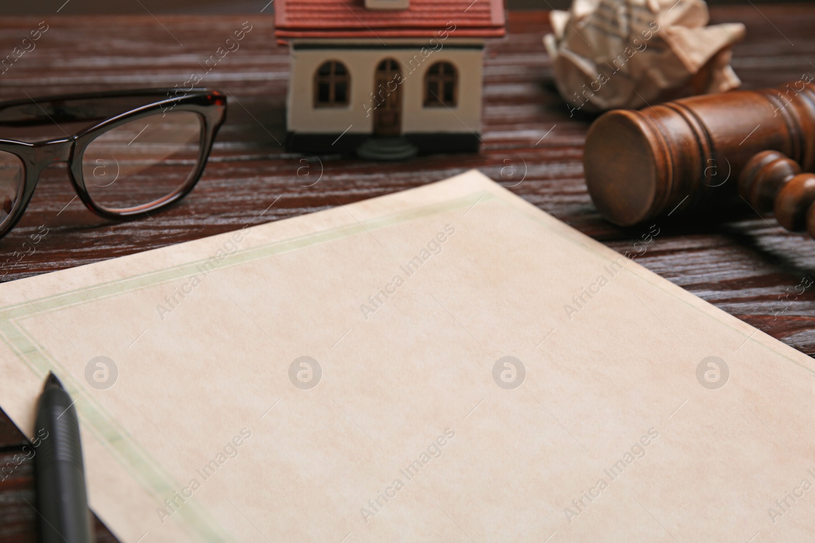 Photo of Last will and testament near house model, glasses and gavel on wooden table, closeup