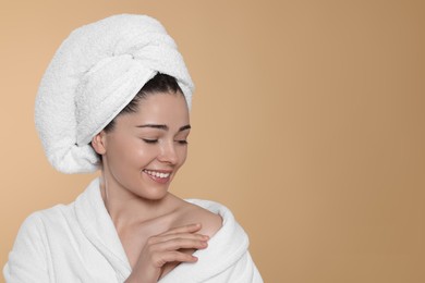 Photo of Portrait of attractive young woman in bathrobe with towel on beige background, space for text. Spa treatment
