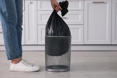 Woman taking garbage bag out of bin at home, closeup