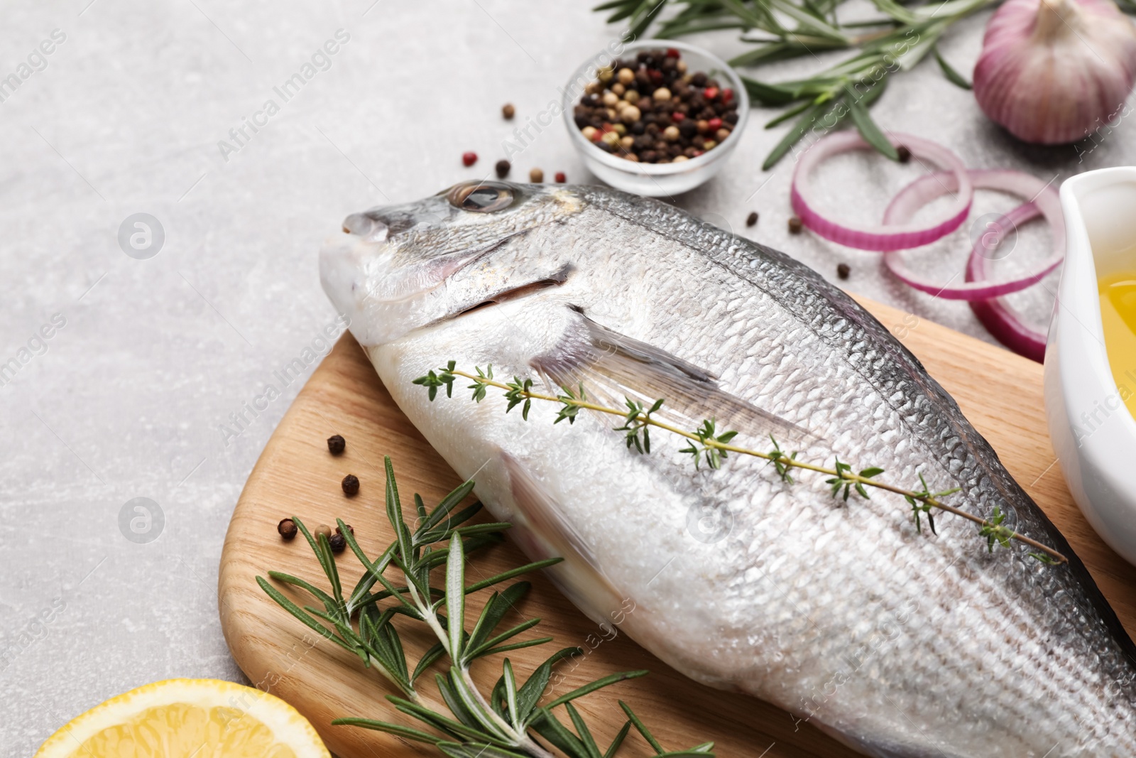 Photo of Fresh raw dorado fish and ingredients on light grey table, closeup