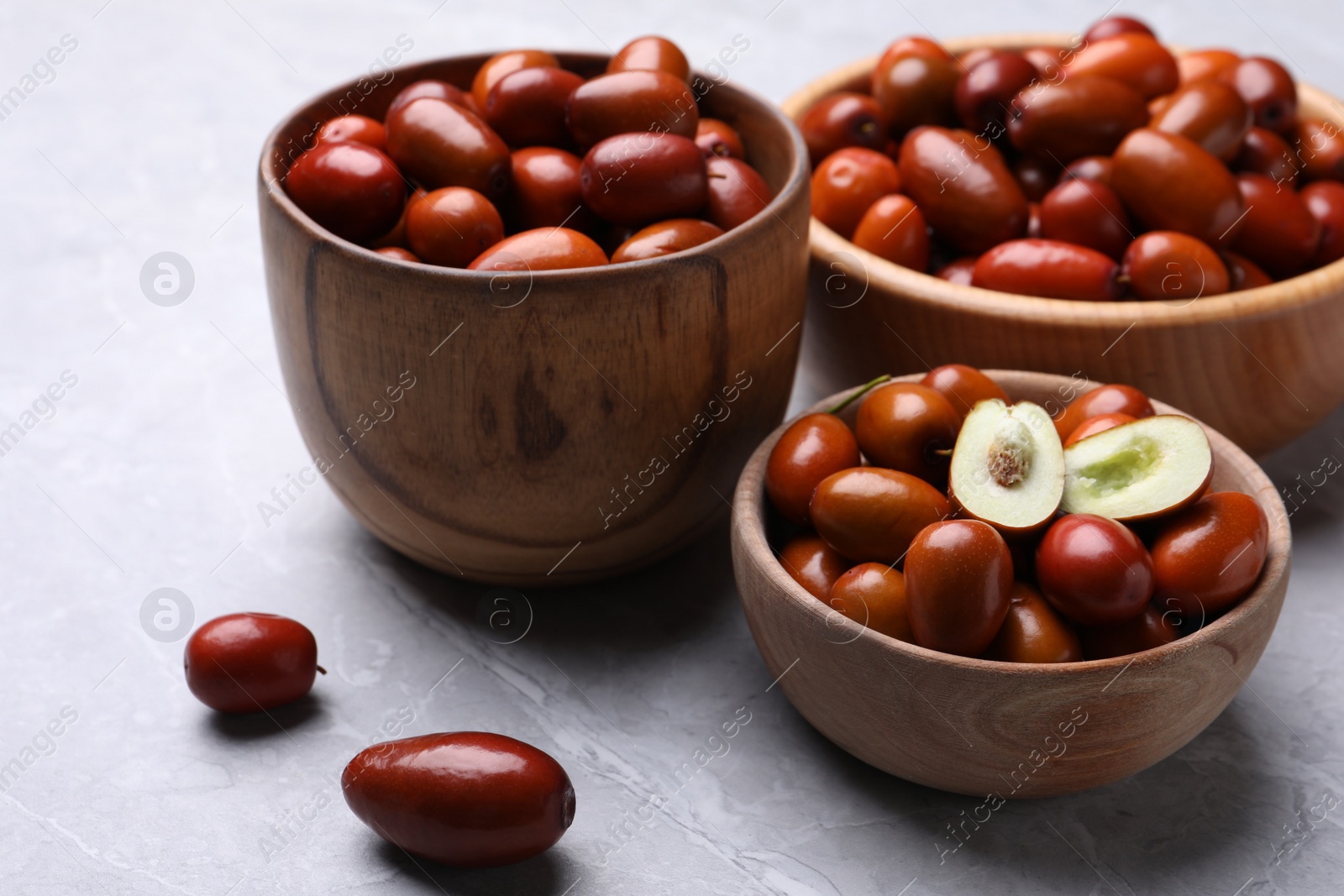 Photo of Fresh Ziziphus jujuba fruits with wooden bowls on light table