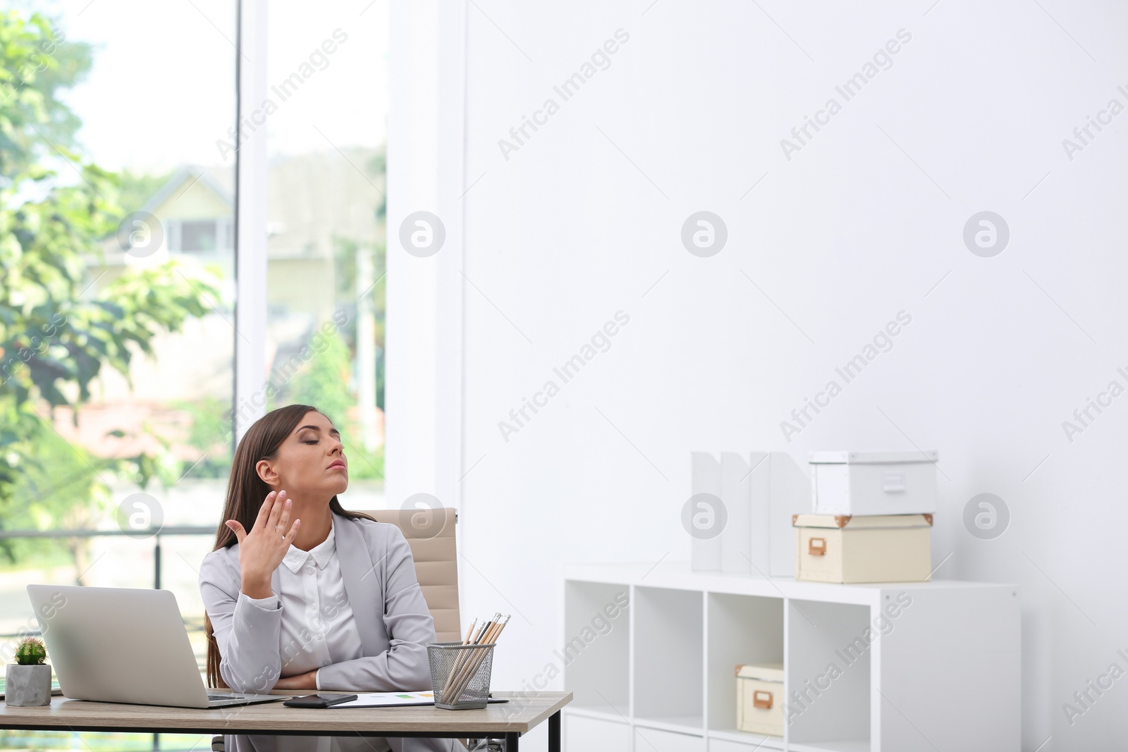 Photo of Young woman suffering from heat in office. Air conditioner malfunction