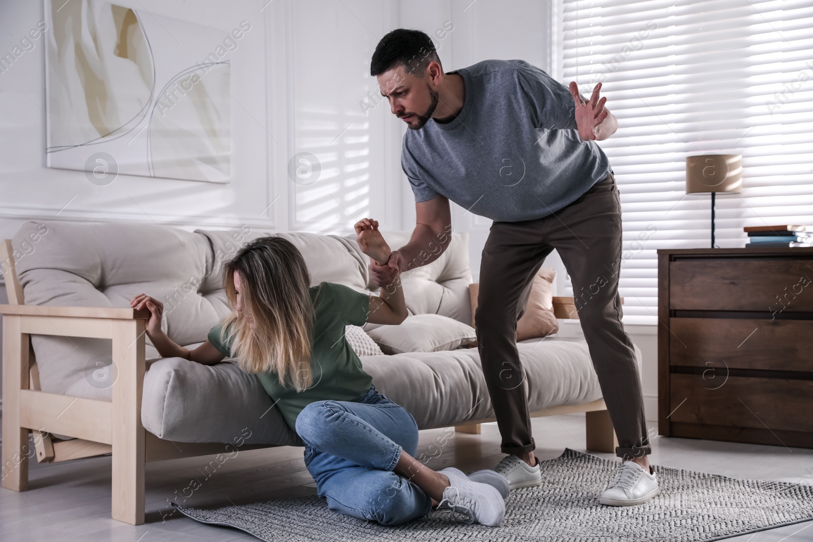 Photo of Man abusing scared woman at home. Domestic violence