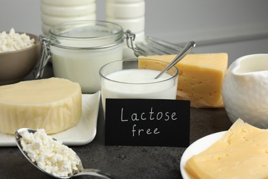 Photo of Many different dairy products and card with phrase Lactose free on grey textured table, closeup