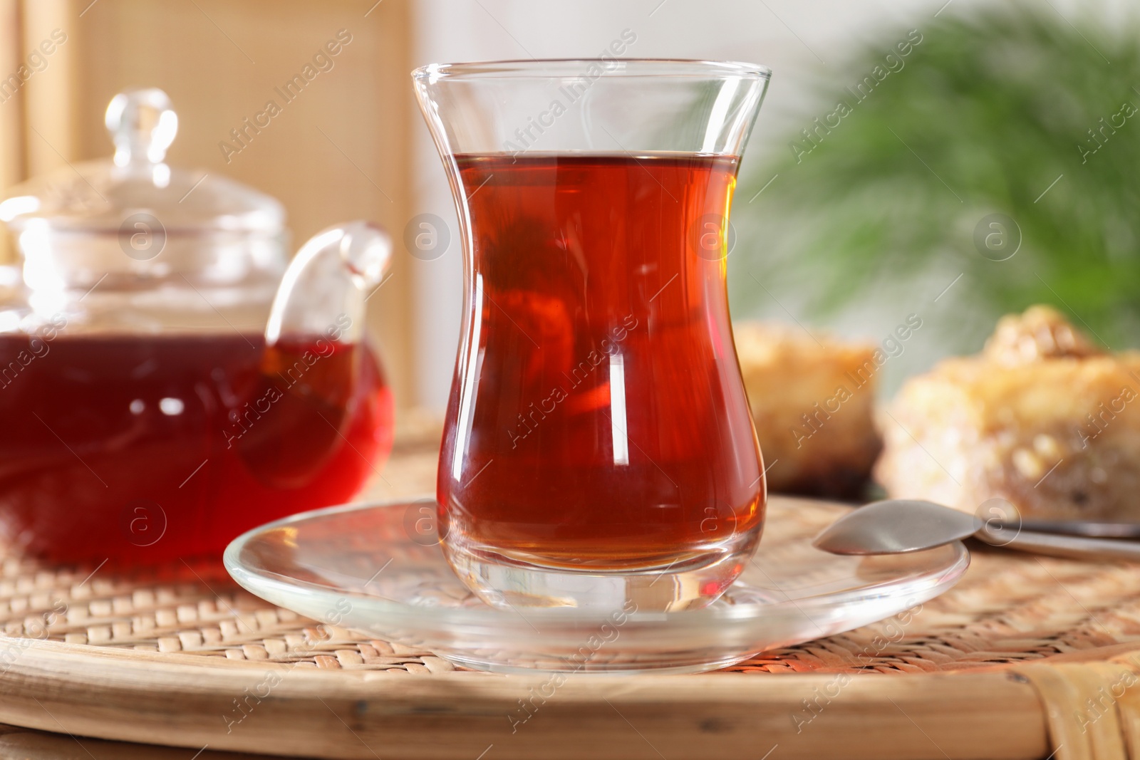 Photo of Traditional Turkish tea in glass on wicker table, closeup