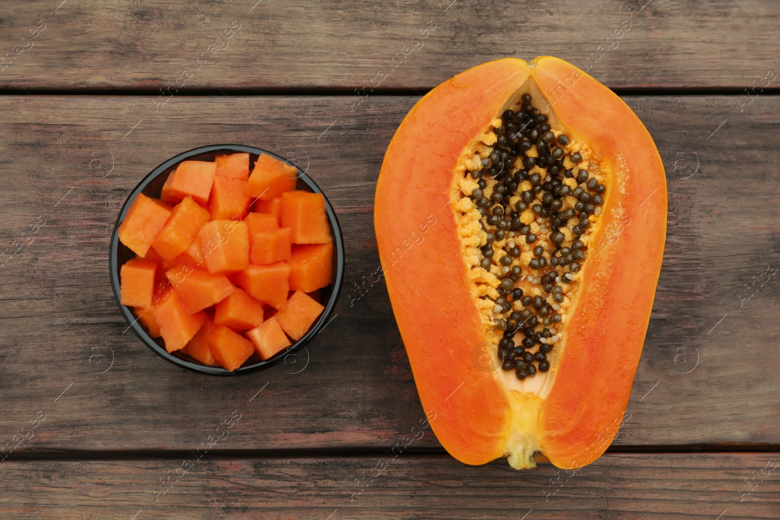 Photo of Tasty cut papaya fruits on wooden table, flat lay