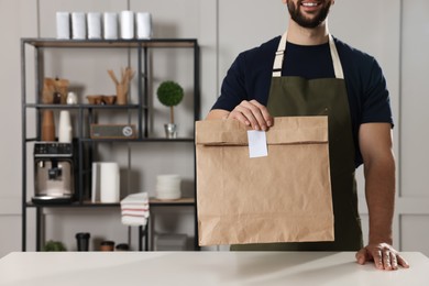 Photo of Worker with paper bag at counter in cafe, closeup. Space for text