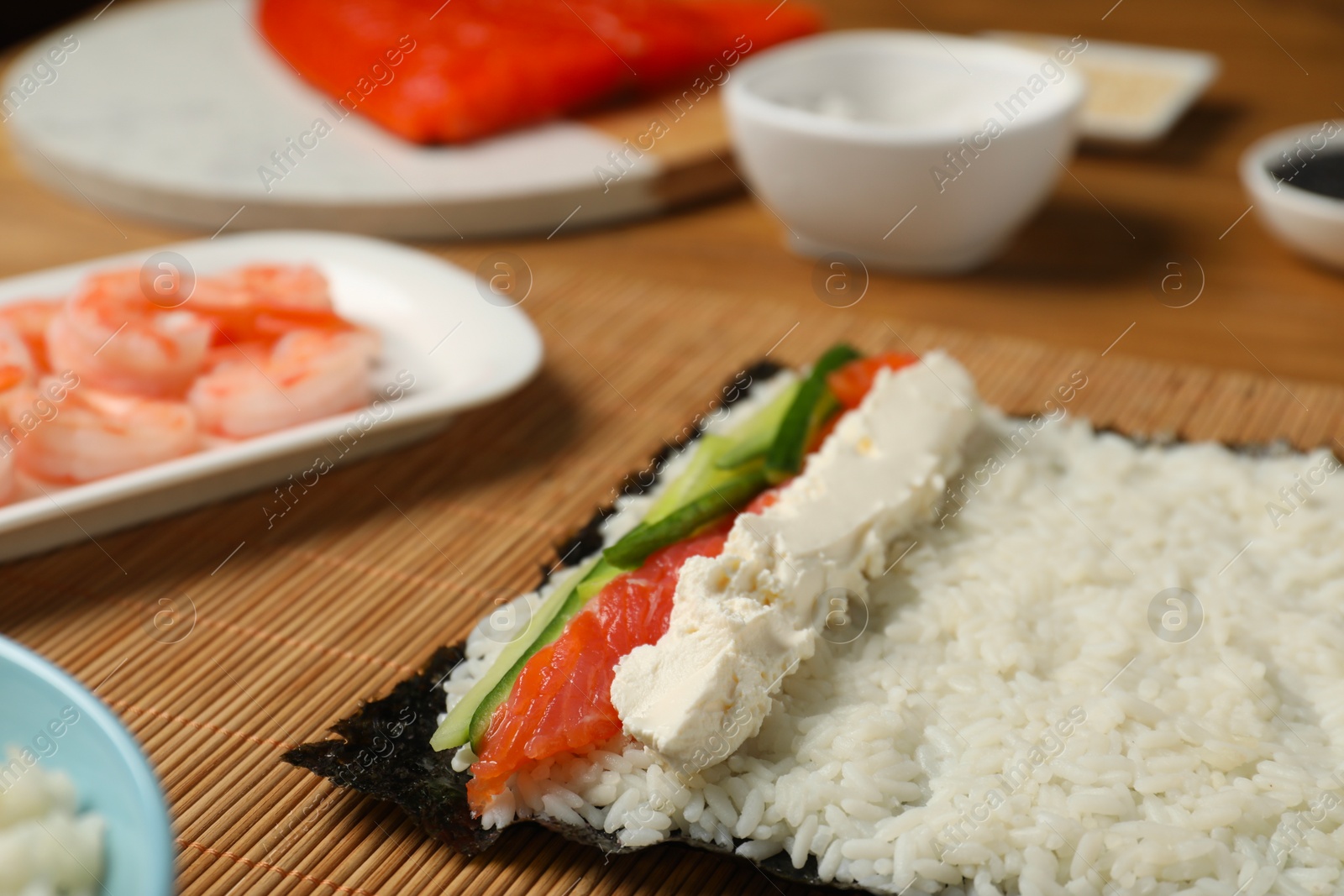 Photo of Unwrapped sushi roll with rice, cucumber, cheese and salmon on table, closeup