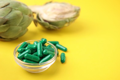 Photo of Bowl with pills and fresh artichokes on yellow background, closeup. Space for text
