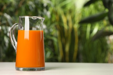 Tasty carrot juice on white table outdoors. Space for text