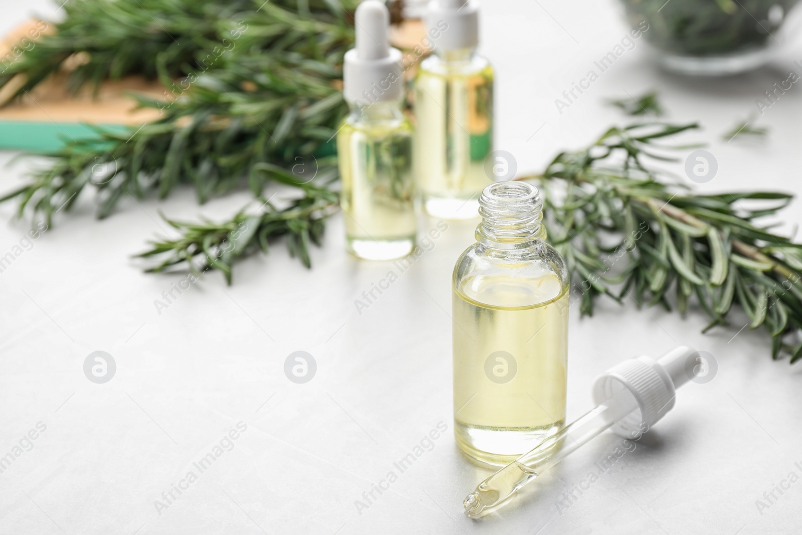 Photo of Bottle of rosemary essential oil on white table. Space for text