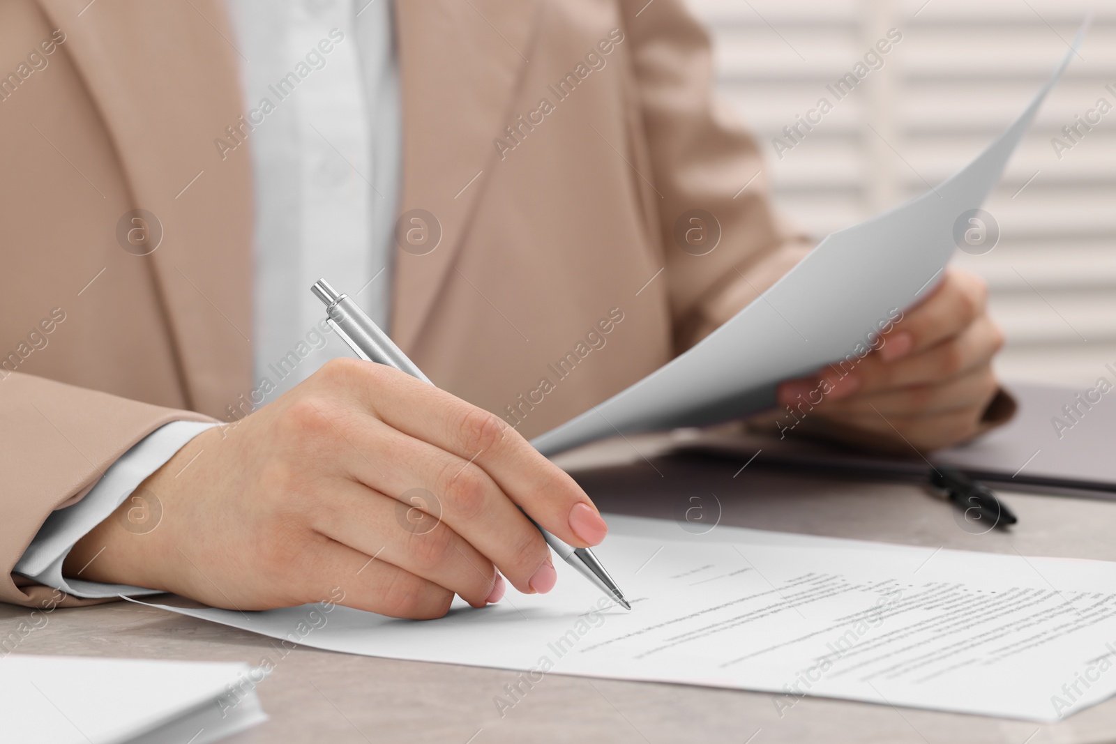 Photo of Woman signing document at table, closeup view