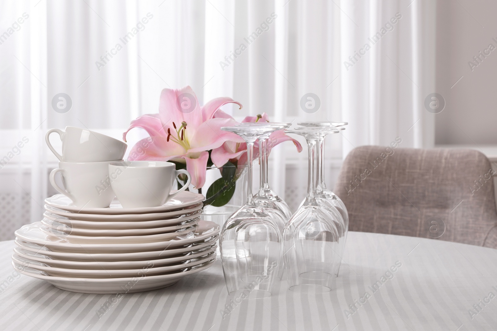 Photo of Set of clean dishware and wine glasses on table indoors