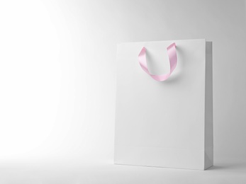 Photo of Paper shopping bag with ribbon handles on white background. Mockup for design