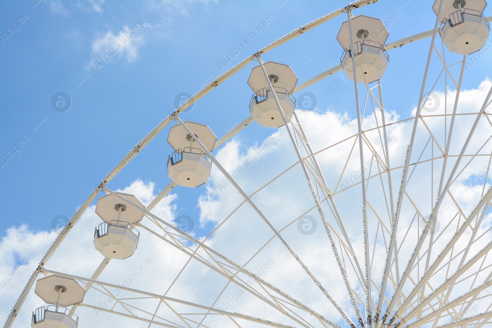 Photo of Large observation wheel against blue cloudy sky, low angle view