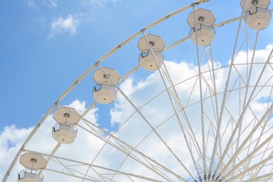 Large observation wheel against blue cloudy sky, low angle view